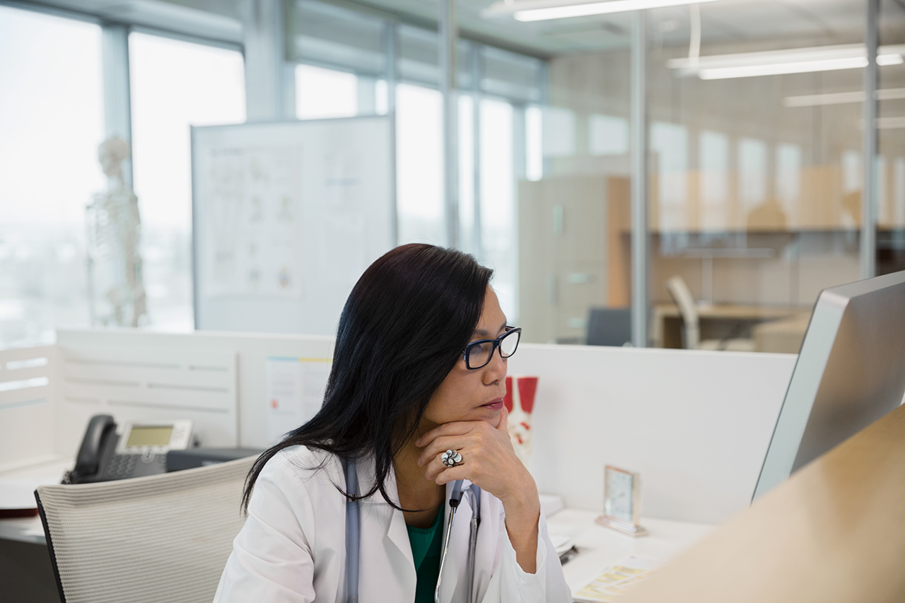 Serious doctor working at computer in clinic office