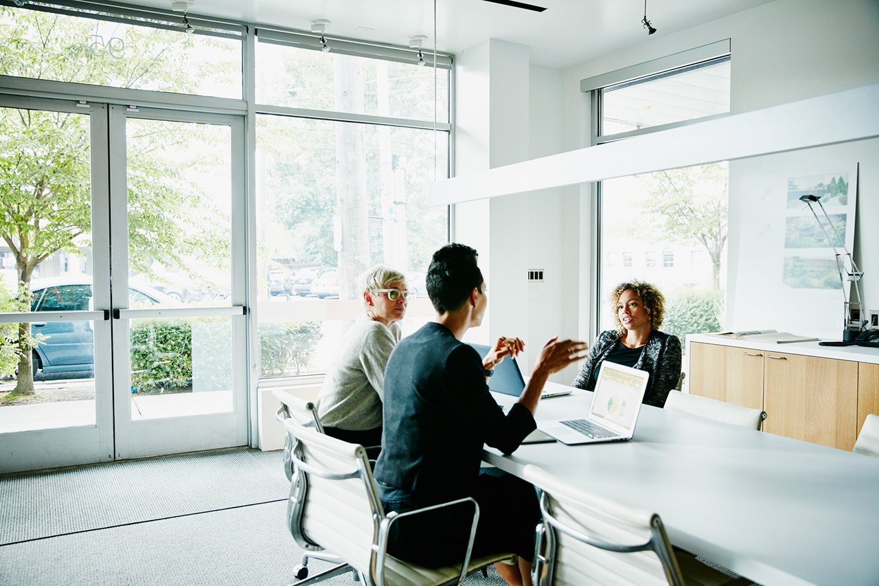 Businesswoman presenting project ideas to colleagues at conference table in office, meeting