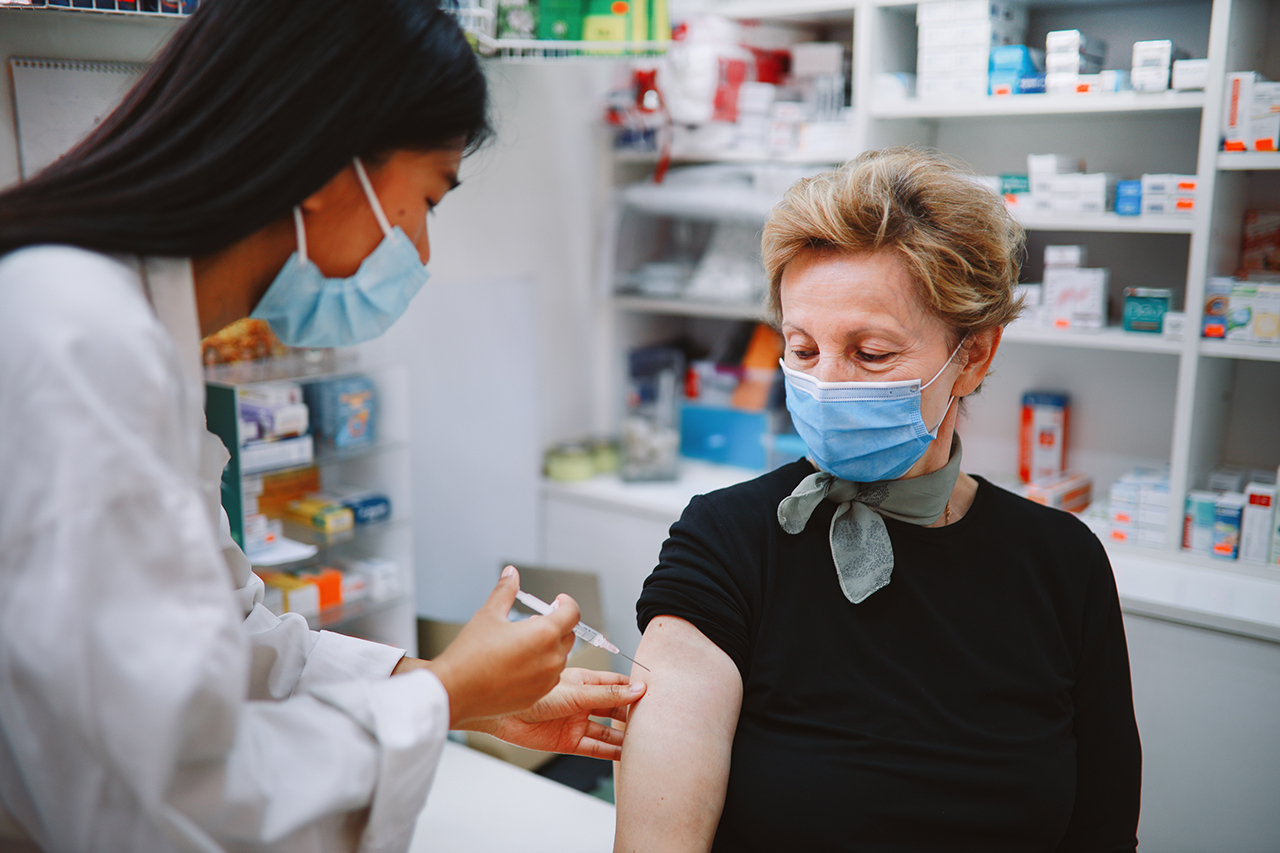 Asian nurse giving flu vaccine to a senior patient in the hospital during the global coronavirus covid-19 pandemic.