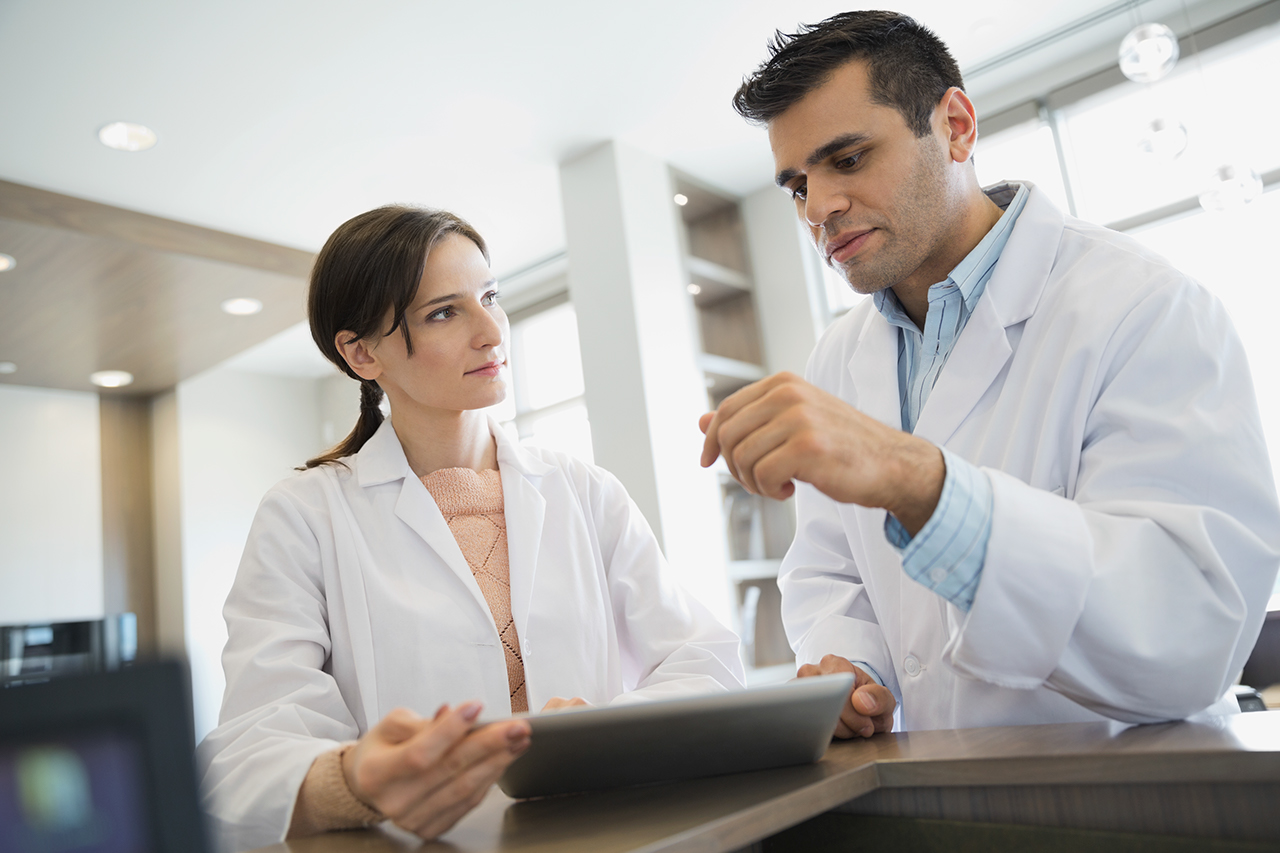 Dentists talking with digital tablet at front desk