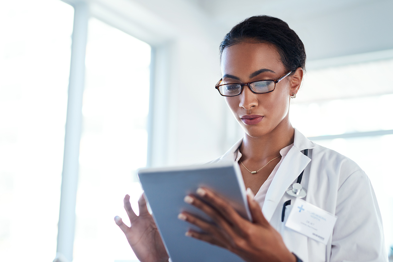 Doctor using a digital tablet in her consulting room