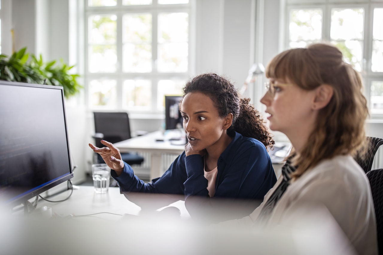 Businesswoman discussing data on screen in office