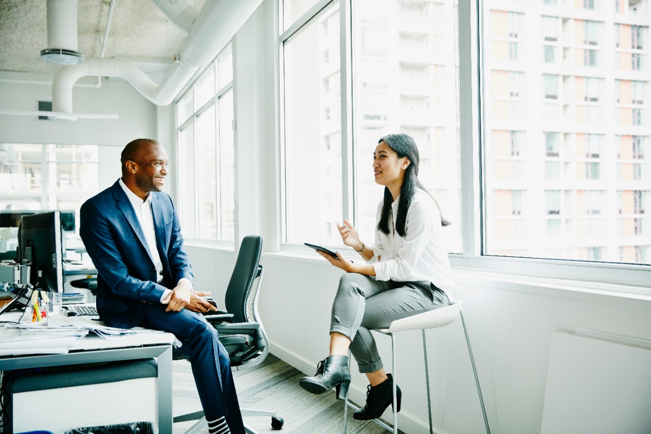 Smiling businessman and businesswoman discussing project at office workstation