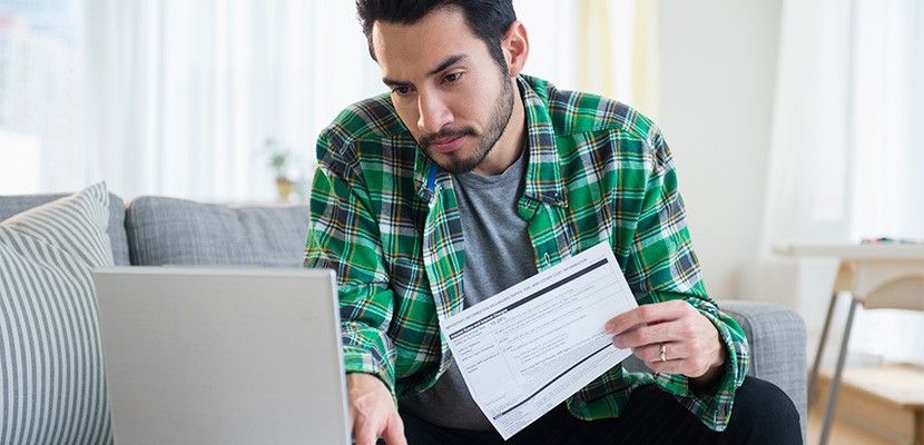 Man paying bills on laptop in living room