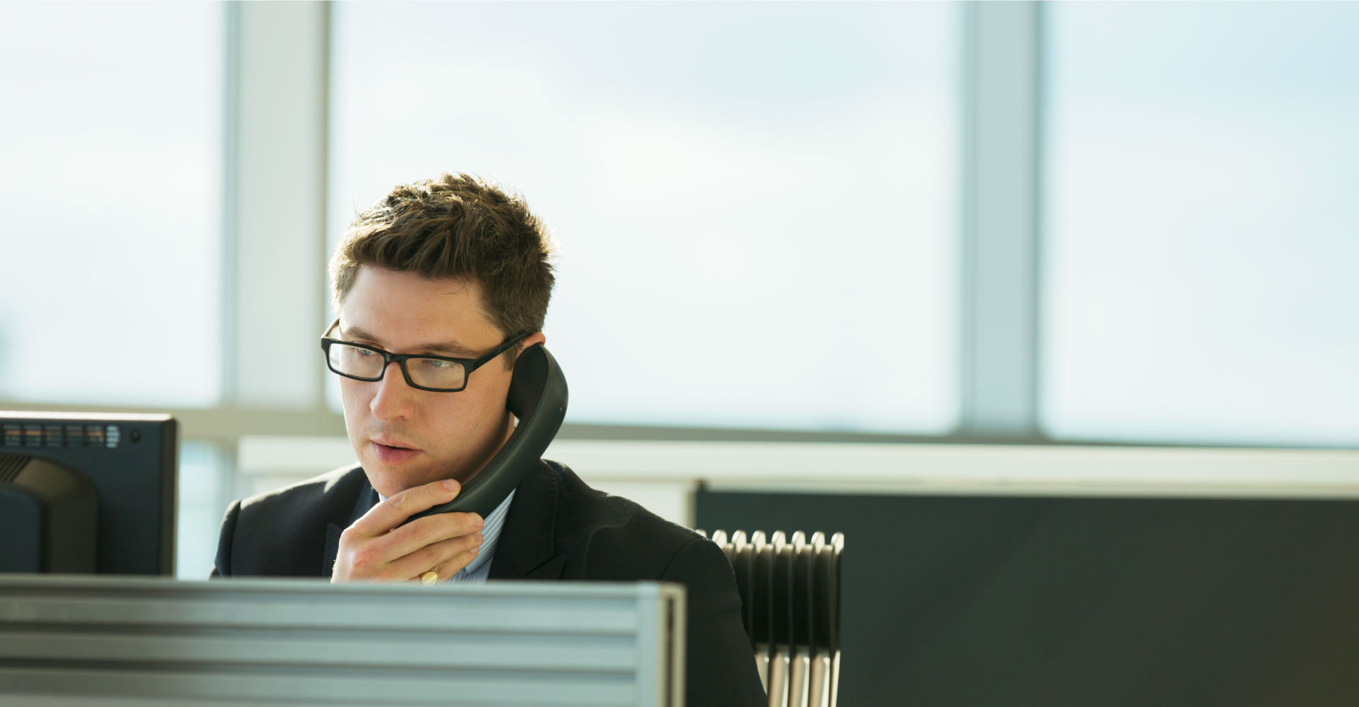 Man looking at computer screen and talking on phone